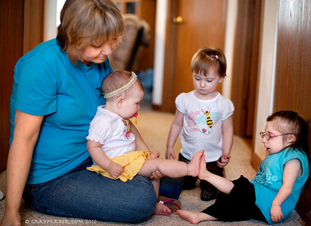 Bridgette compares foot-sizes with her 10 month old niece.  At 21 years old, Bridgette wears an infant size 2 shoe - so her niece has a bigger foot.